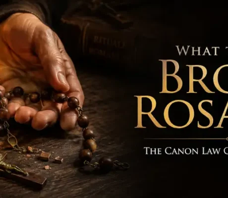 A broken wooden rosary and a frayed scapular resting on a dark wood table beside a glowing beeswax candle, illustrating how to dispose of blessed items.